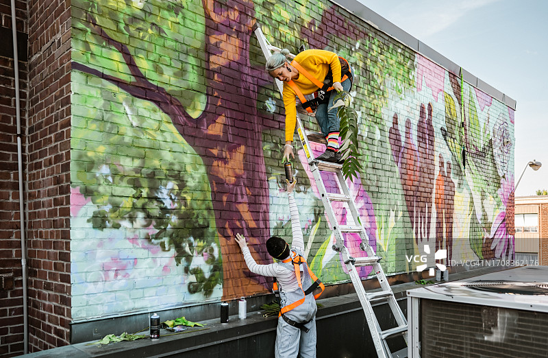 在屋顶画壁画的两名女艺术家图片素材