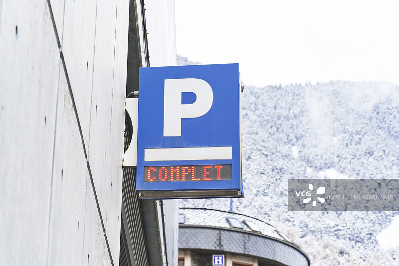 寒冷天气中，建筑物外墙上蓝色停车标志的低角度正面图图片素材
