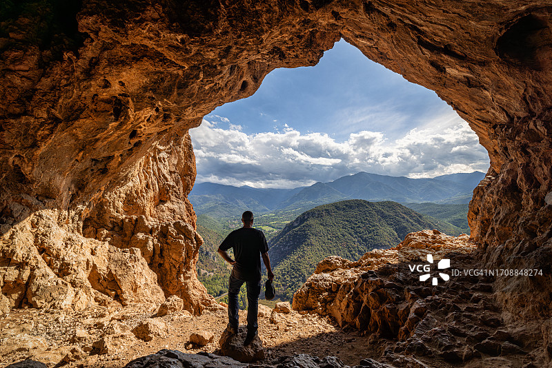 男人站在洞穴中，看着山景图片素材