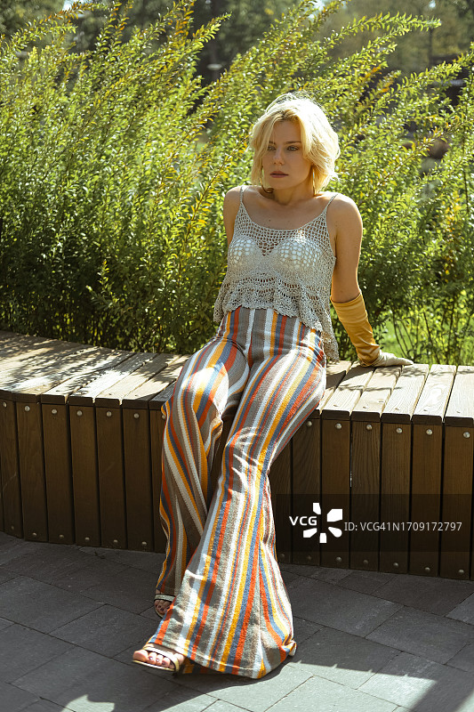 年轻女人穿着喇叭裤在阳光明媚的日子里休息图片素材