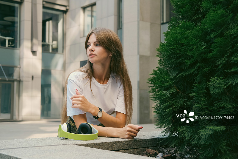 靠在栏杆上、背景是办公楼的年轻女人图片素材