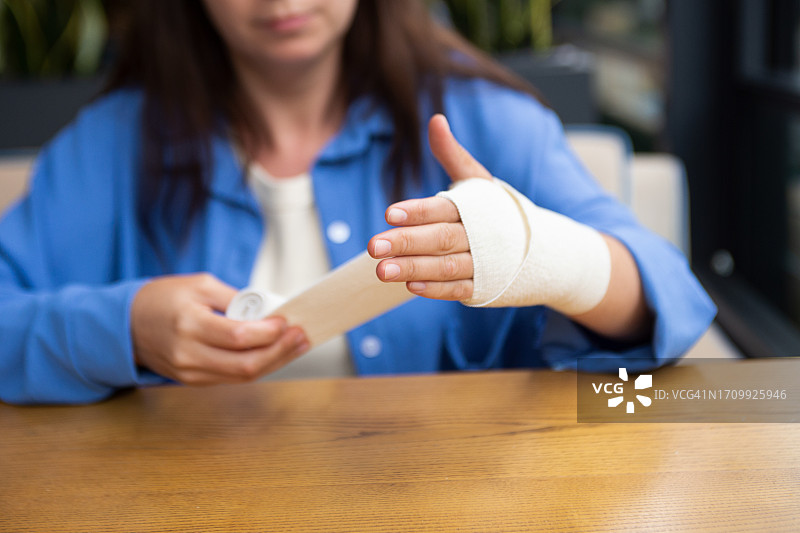 缠绕弹性绷带的女性手部特写，关节治疗概念图片素材