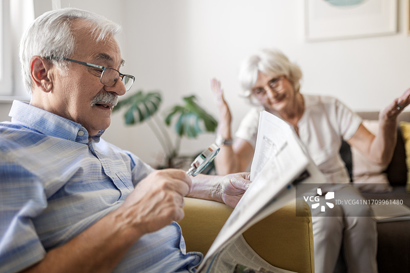 老年男人使用放大镜阅读图片素材