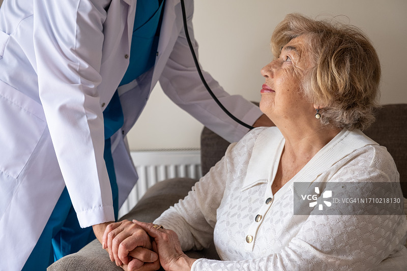 年轻医生帮助站在客厅里的年长妇女图片素材