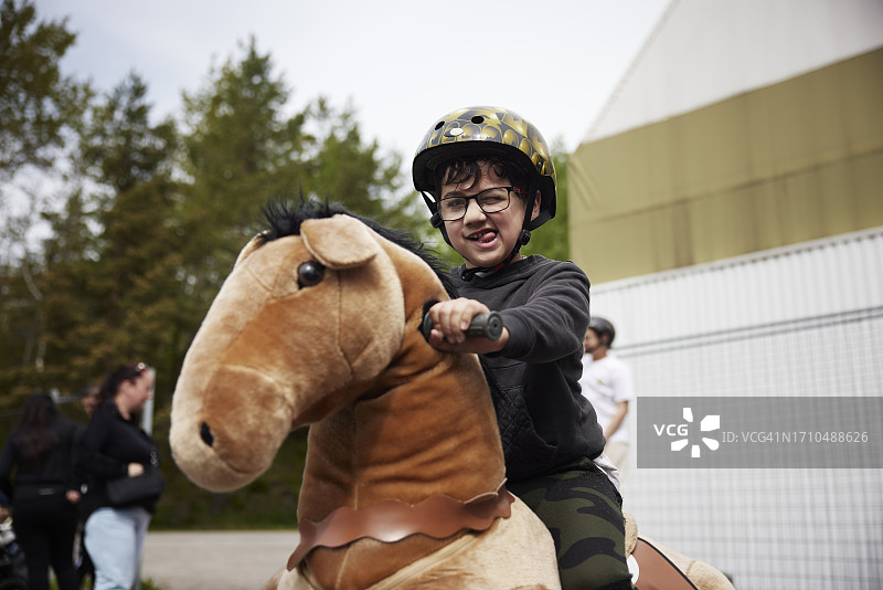 在户外骑轮马玩耍的快乐男孩肖像图片素材