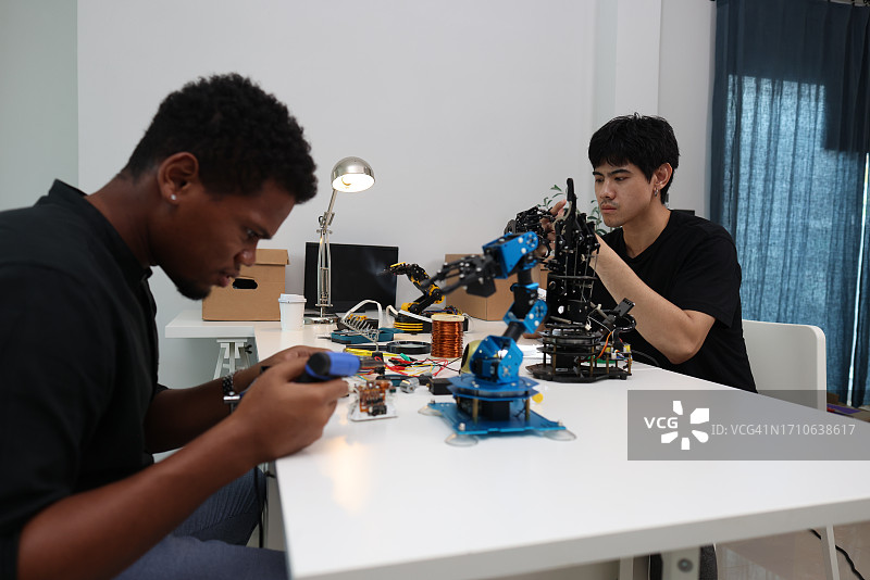 两位机电一体化工程师专心组装和编程机器手图片素材