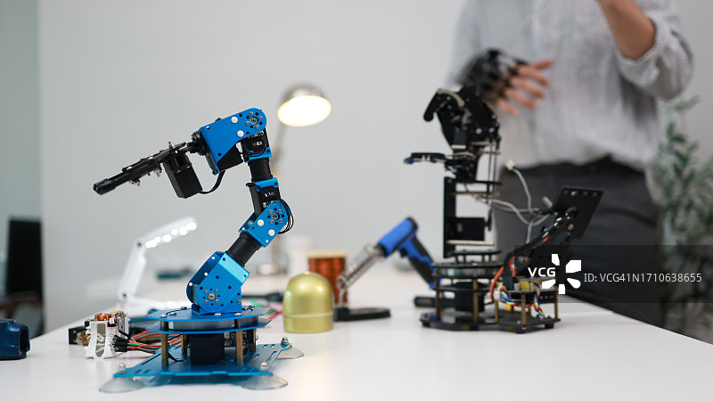 年轻的机械电子工程师正在检查和分析新项目的机械臂图片素材