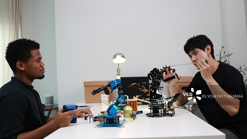 两位机电一体化工程师专心组装和编程机器手图片素材