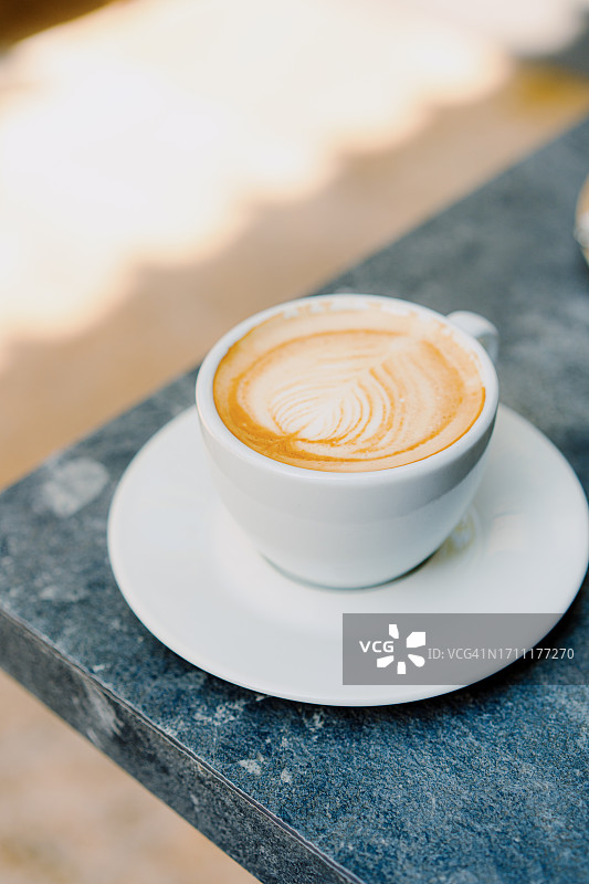 灰色桌上带有拿铁艺术的卡布奇诺图片素材
