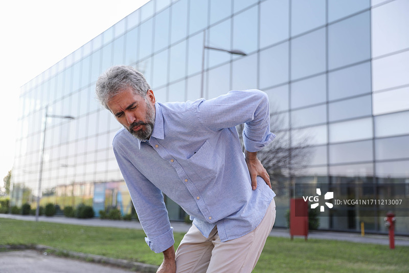公司门前背部受伤的中年商人图片素材