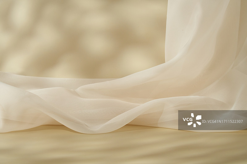 化妆品浅米色背景样机，薄透织物在背景中呈波浪状。抽象米色构图，产品展示留白图片素材