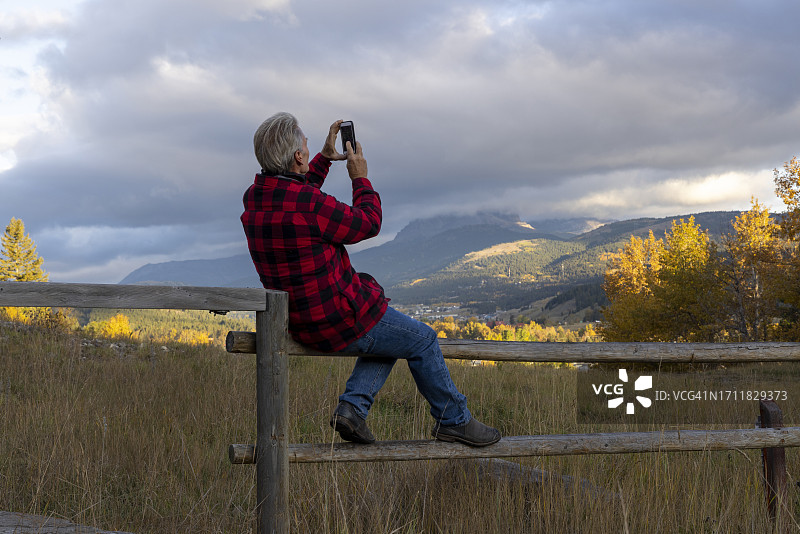 中年男人在日出时分于草地围栏上放松图片素材