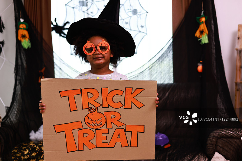 万圣节装扮的兄弟姐妹，手提“不给糖就捣蛋”的桶图片素材