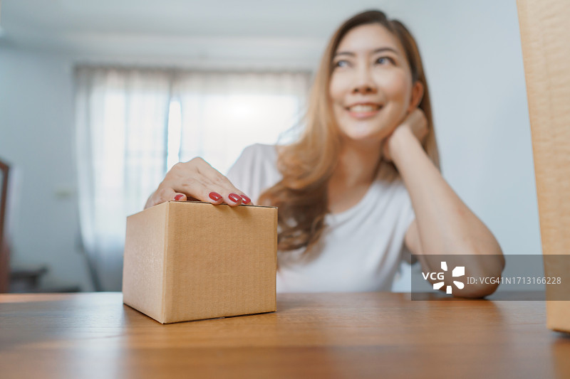 女商人检查订单，周围是包裹箱。拥有纸板箱的在线订单和配送业务的女老板。图片素材