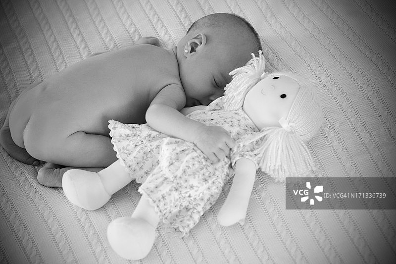 抱着玩偶睡觉的新生儿图片素材