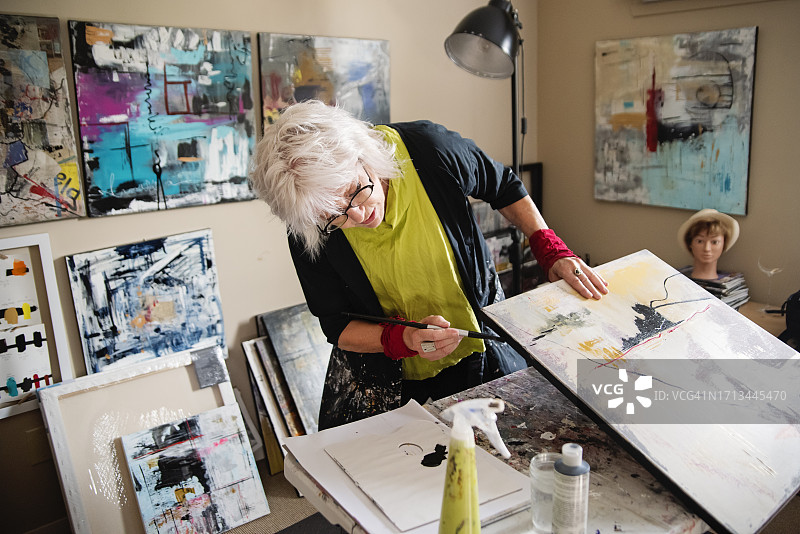 在工作室绘画的年长女艺术家图片素材