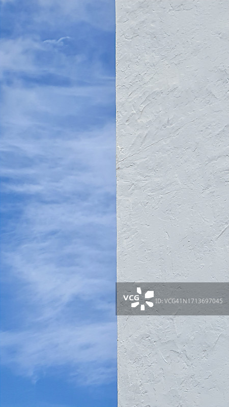 粗糙的白墙和略带阴云的蓝天图片素材