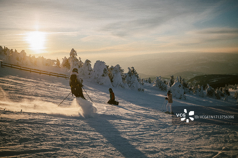 人们在日落时滑雪和滑雪板图片素材