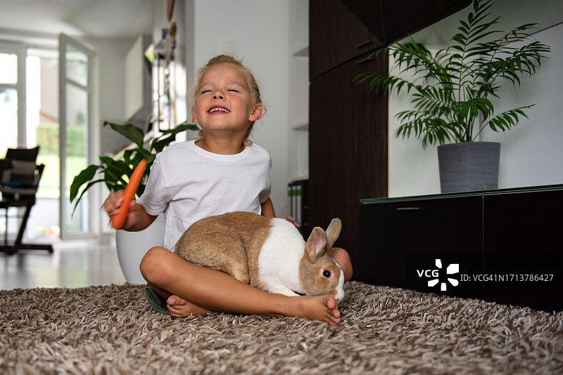 快乐的小男孩在家与兔子玩耍图片素材