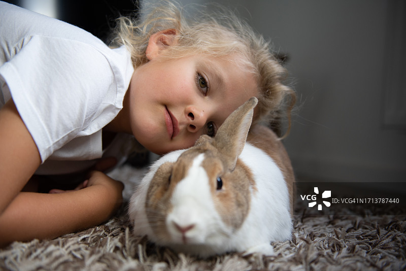快乐的小男孩在家与兔子玩耍图片素材