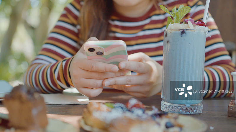 年轻女人在咖啡馆使用手机与朋友共度时光，社交和个人享受概念图片素材