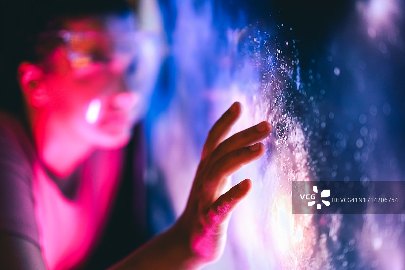 一个人触摸数字界面，与未知事物互动和宇宙探索。图片素材