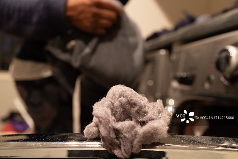 站在烘干机前的黑人女性，烘干机门上有棉绒球图片素材