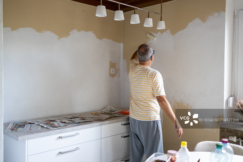 用油漆滚筒粉刷墙壁的中年男人图片素材