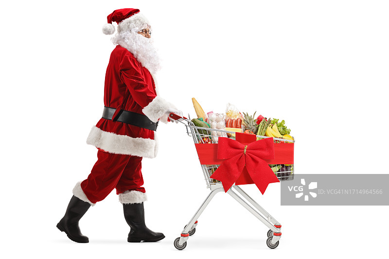 圣诞老人推着带红色蝴蝶结的购物车全身照图片素材