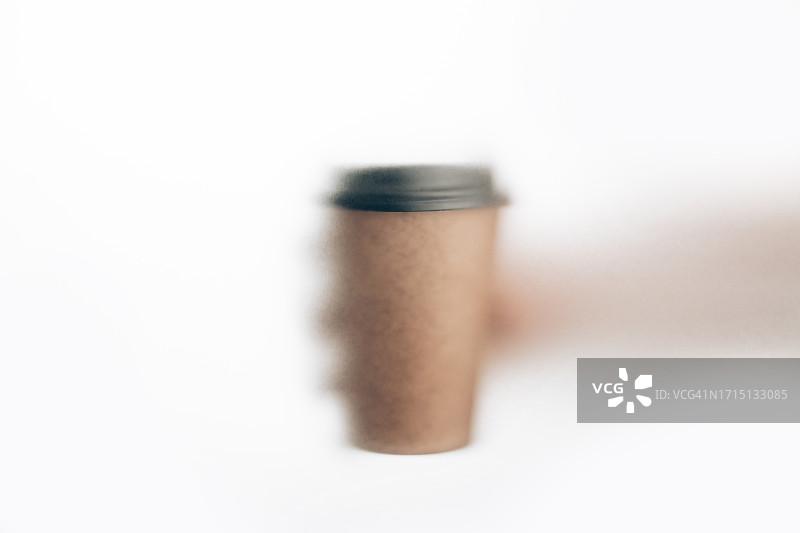 手持一次性纸杯（透过透明膜拍摄，散焦）图片素材