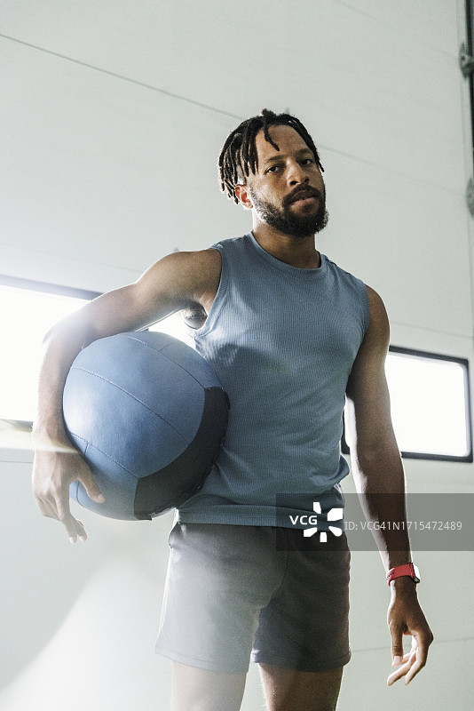 健身俱乐部里手 holding 药球的自信年轻人肖像图片素材