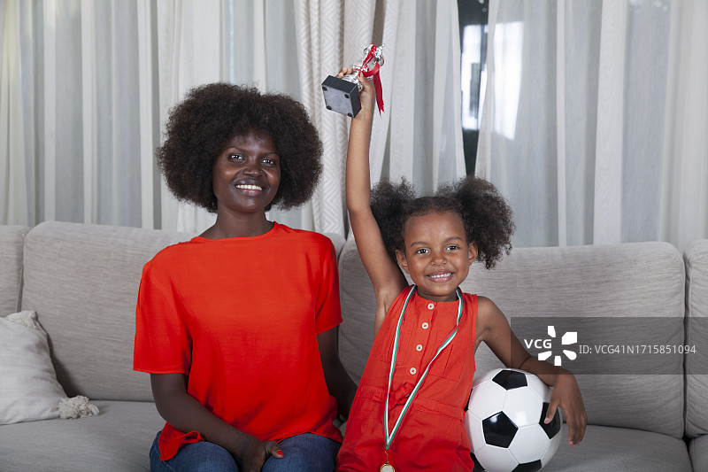 非洲裔母亲为女儿手中的奖牌和奖杯感到兴奋图片素材