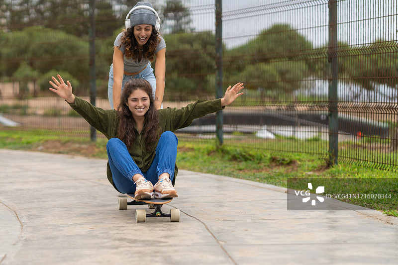 朋友们玩滑板，互相推着对方图片素材