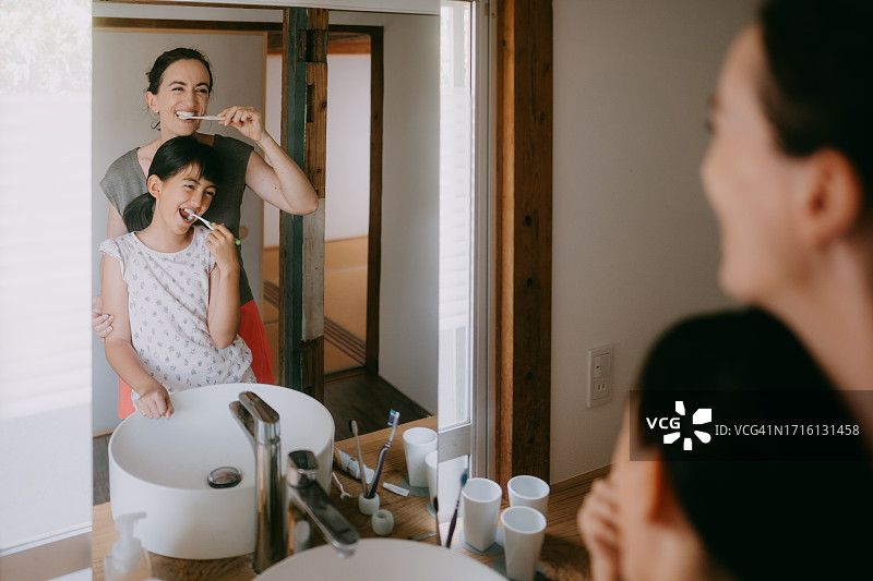 母亲和年幼的女儿在家中浴室刷牙图片素材