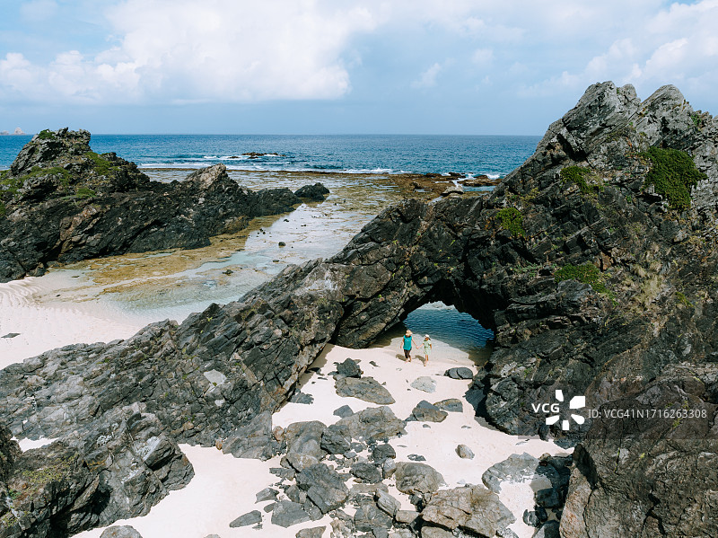 母亲和孩子探索崎岖海岸线的航拍图片素材