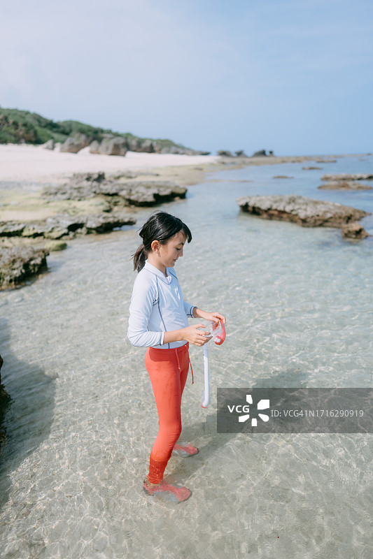 戴着浮潜装备站在清澈热带水域的年轻女孩图片素材