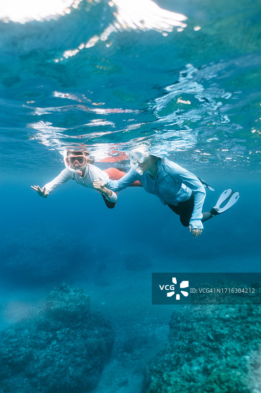 母子在清澈的蓝色海水中浮潜图片素材