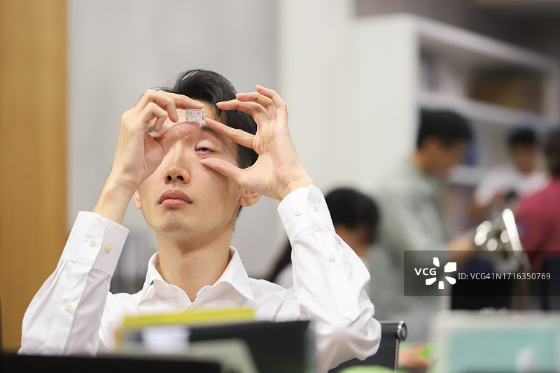 穿衬衫的男办公室工作人员正在用眼药水护理眼睛图片素材