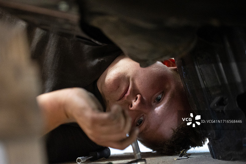 年轻汽车修理工在汽车修理店修理汽车图片素材