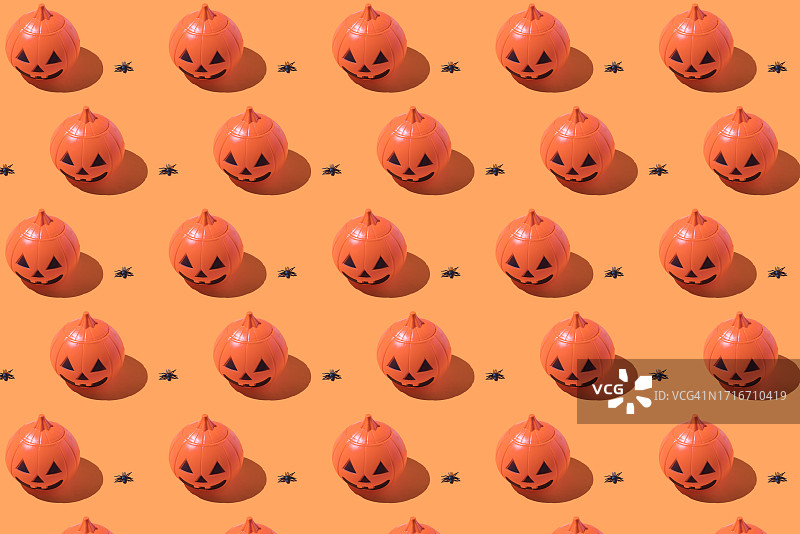 橙色背景上塑料万圣节南瓜灯和蜘蛛图案，万圣节庆祝、亡灵节、昆虫、惊吓、恐惧概念图片素材
