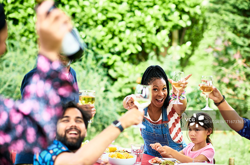在花园派对上与家人举杯的快乐中年黑人妇女图片素材