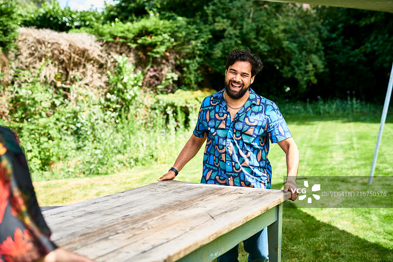 快乐的亚洲男人和朋友在花园里抬桌子图片素材