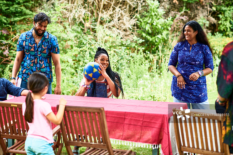 中年妇女在花园桌旁坐着笑扔球图片素材