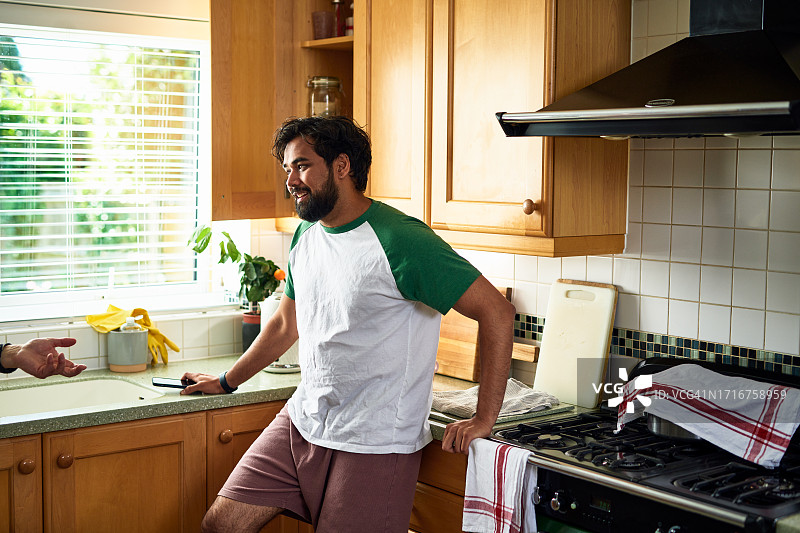 中年男人在厨房，智能手机放在台面上图片素材