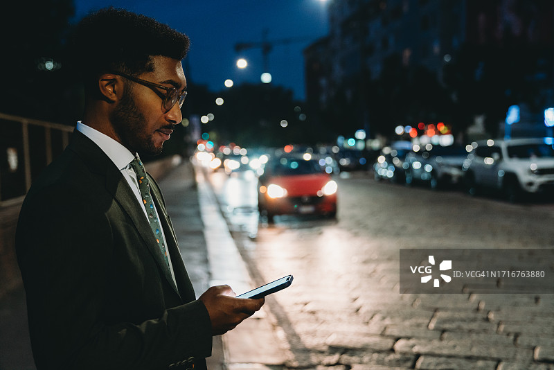 夜晚在城市里使用手机的年轻商务男士图片素材