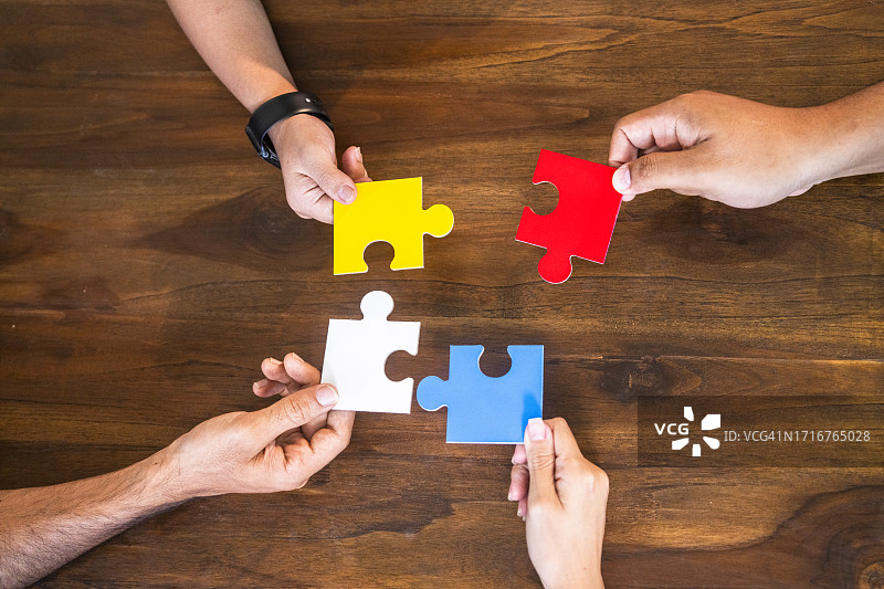 一群无法辨认的人在地板上拼合拼图的局部照片图片素材