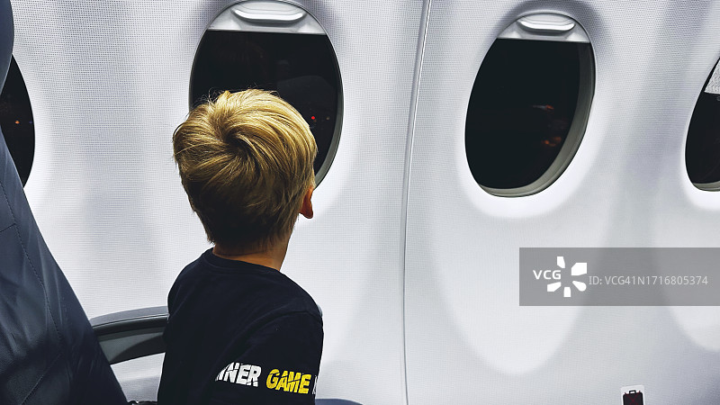 男孩看着飞机窗外图片素材