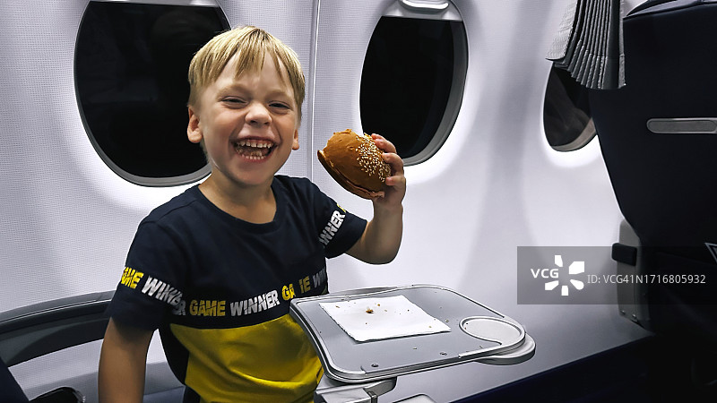 男孩在飞机上吃汉堡包图片素材