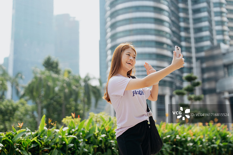 在城市里使用智能手机的年轻亚洲女性图片素材