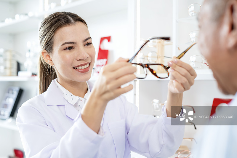 女验光师为年长的男顾客在眼镜店试戴眼镜，保护眼睛图片素材